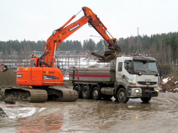 Sisu e12 470 ja Doosan DX 235 LCR
Osa Rantaväylän tunnelityömaalta nousevasta maamassasta ei kelpaa täyttömaaksi. Biomaan Doosan lastaa Sisuun käsittelyyn lähtevää ainesta. 
Avainsanat: Sisu Doosan Rantaväylä Tunnelityömaa Tampere