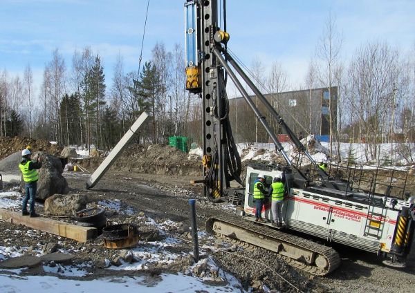 Paalujuntta
Juntta lataa paalut  vetämällä ne vaijerilla puomiin taakin alle. Aasialaiset vieraat seuraavat ohjaamon astinlaudalla kiinnostuneena käyttäjän työskentelyä yhden videoidessa tapahtumaa penkalta.
Avainsanat: Paalujuntta